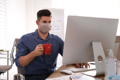 Photo of Worker with mask in office. Protective measure during COVID-19 pandemic