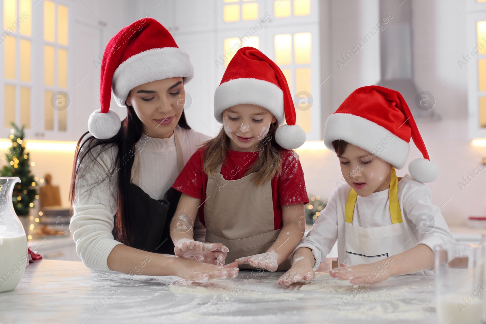 Photo of Mother with her cute little children making Christmas cookies in kitchen