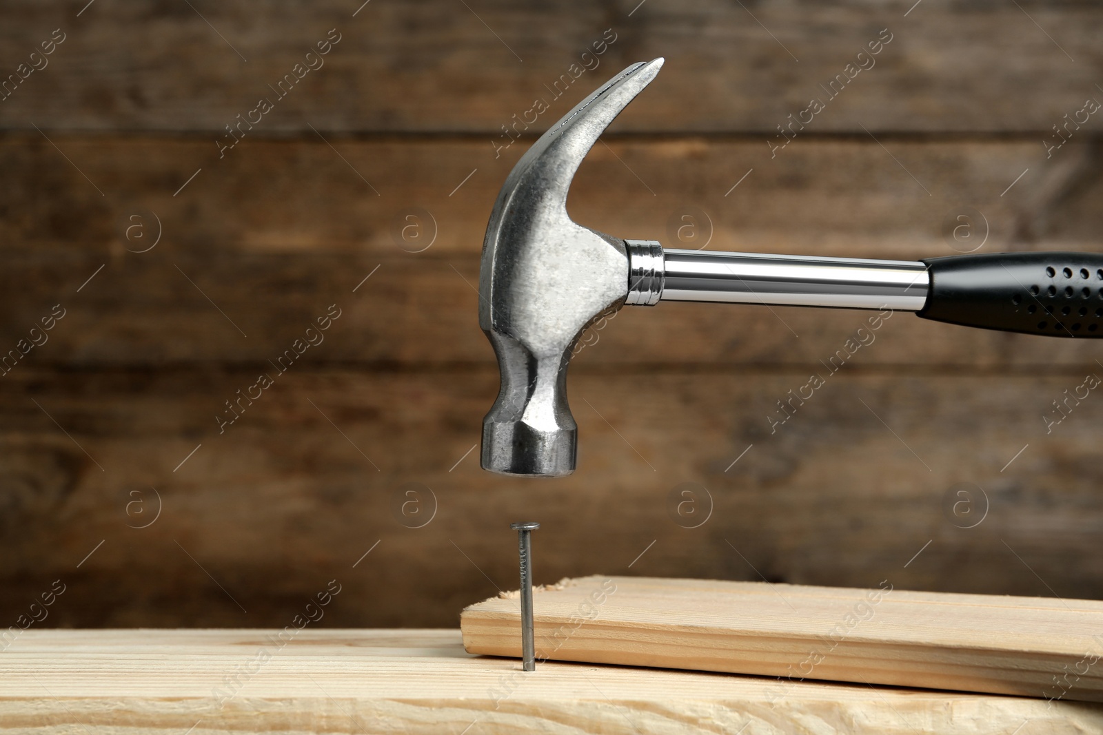 Photo of Hammering nail into plank against wooden background