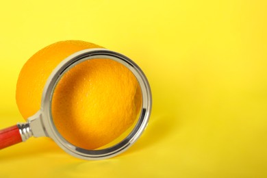 Cellulite problem. Orange and magnifying glass on yellow background, space for text