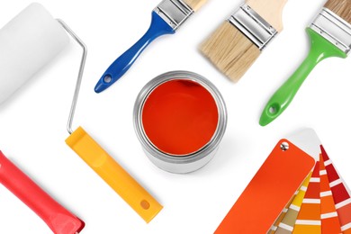 Photo of Can of orange dye, paint chips, roller and brushes on white background, top view