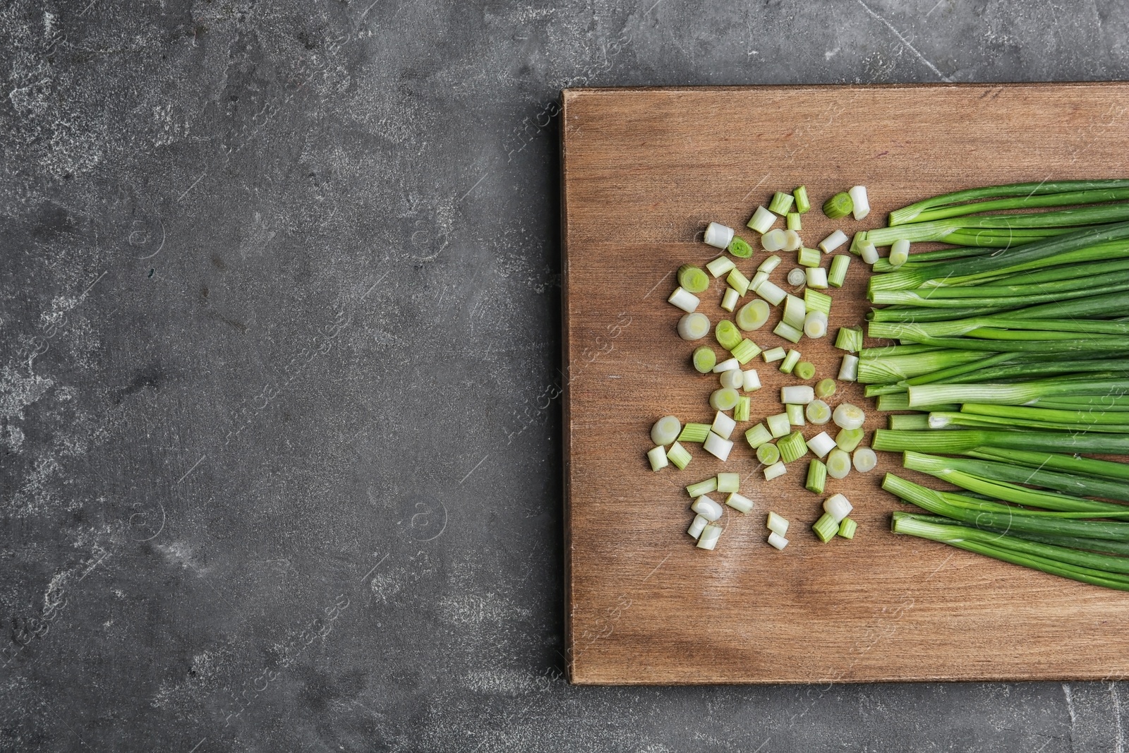 Photo of Fresh green onion on wooden board, top view