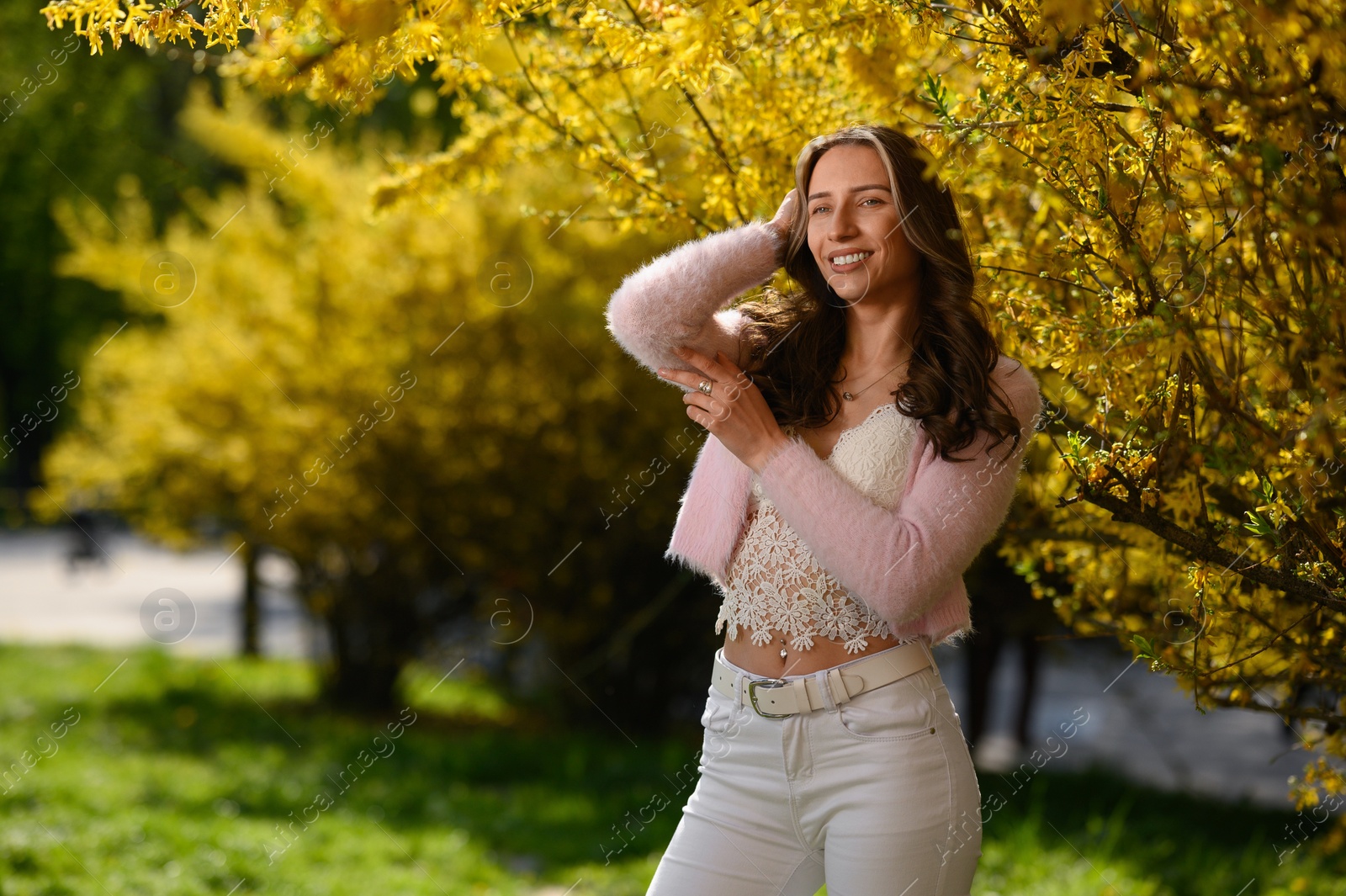 Photo of Beautiful young woman near blossoming shrub on spring day, space for text