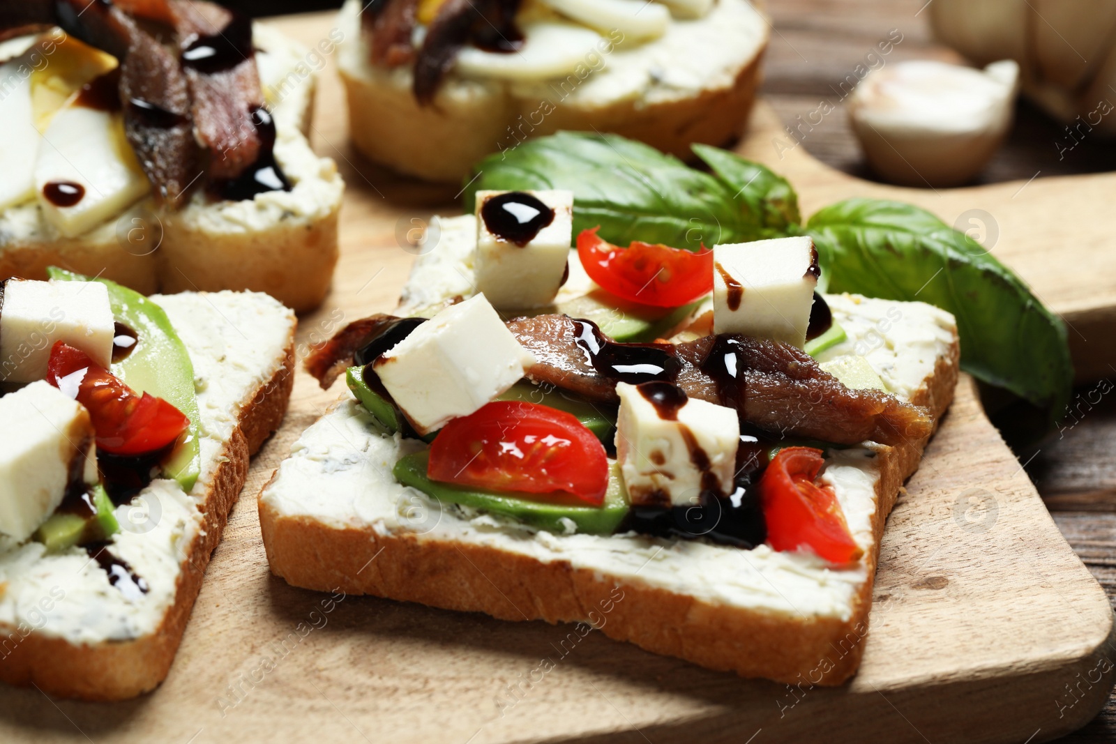 Photo of Delicious sandwiches with anchovies, cheese and tomato on wooden table, closeup