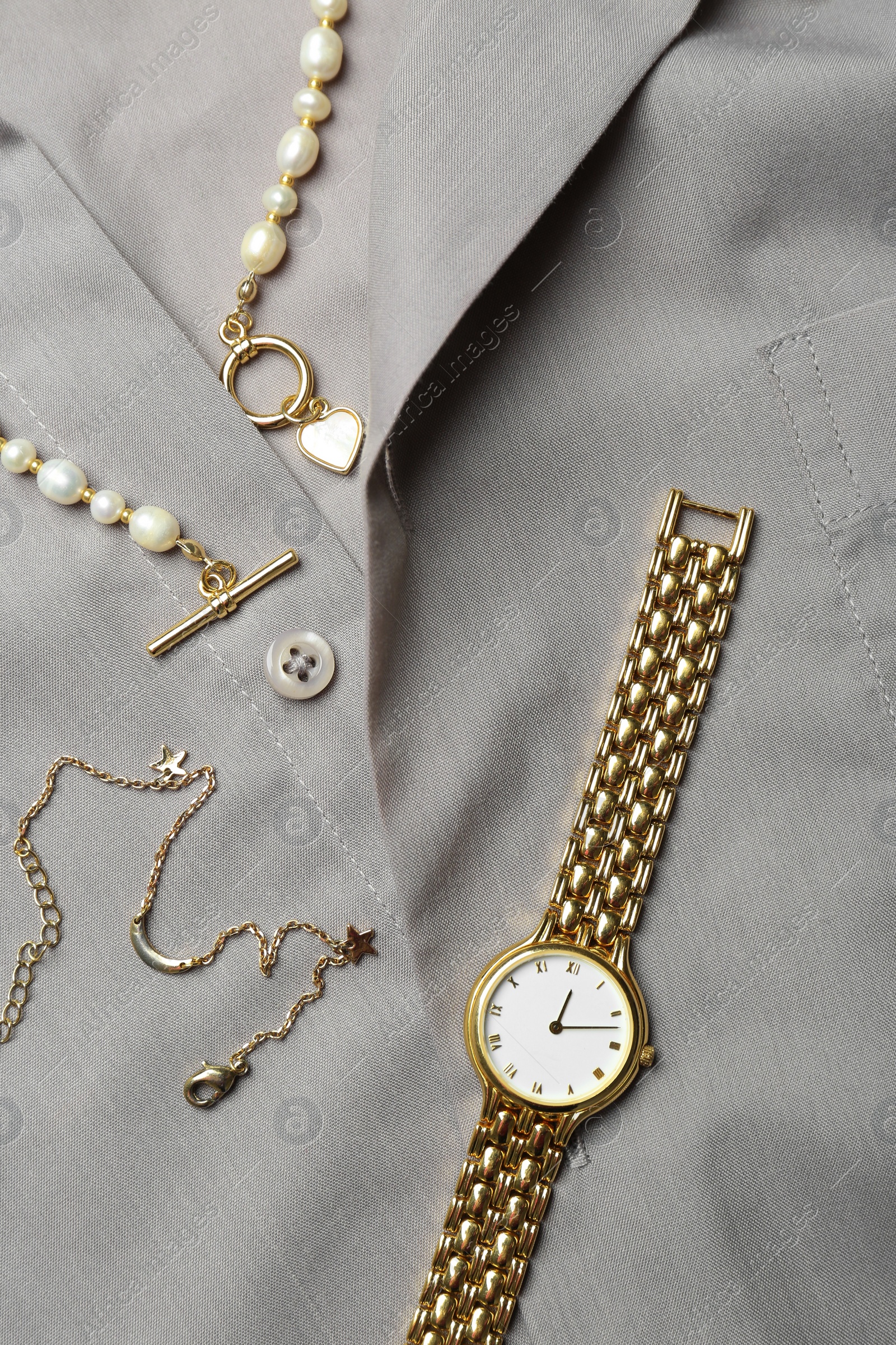 Photo of Different elegant jewelry on grey shirt, flat lay