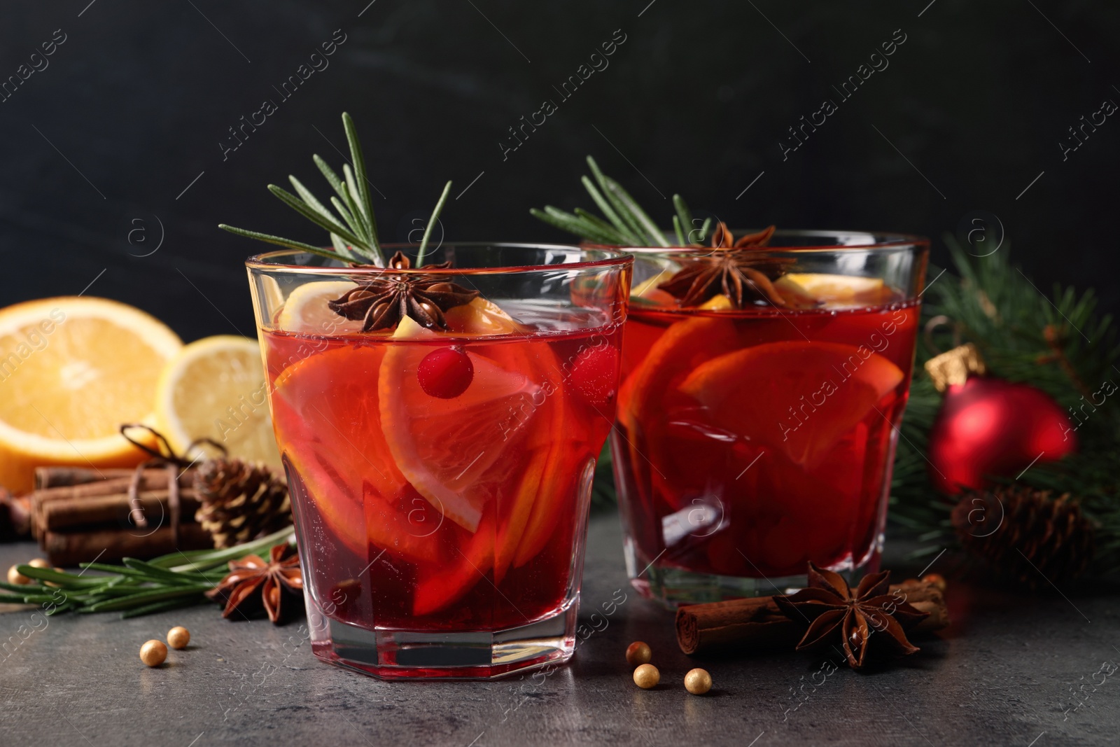 Photo of Delicious punch drink with cranberries, orange and spices on grey table