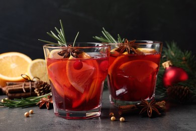 Delicious punch drink with cranberries, orange and spices on grey table