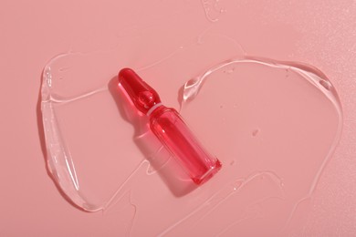 Photo of Skincare ampoule on pink surface with gel, top view