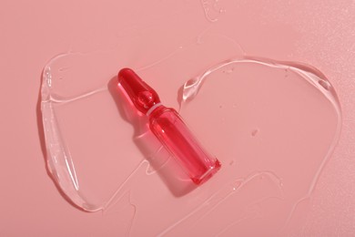 Skincare ampoule on pink surface with gel, top view