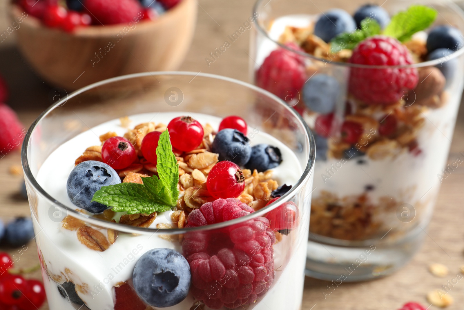 Image of Tasty dessert with yogurt, berries and granola on wooden table, closeup