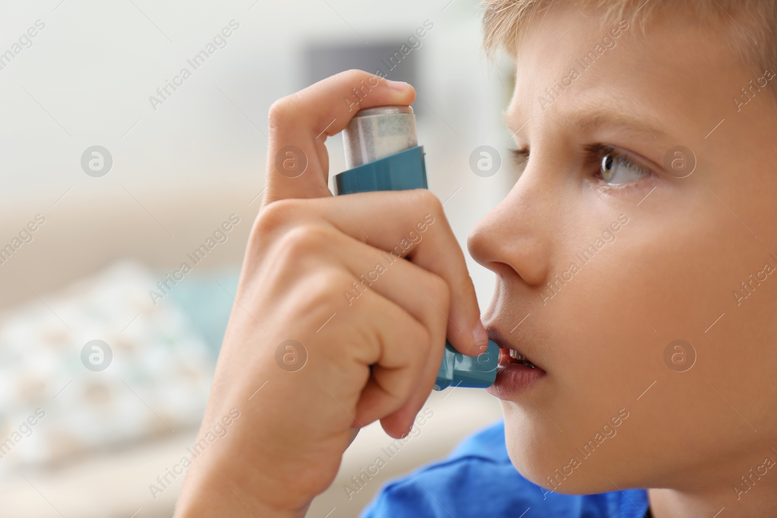 Photo of Little boy using asthma inhaler on blurred background