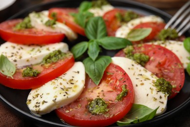 Plate of delicious Caprese salad with pesto sauce on table, closeup