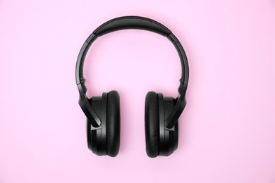 Photo of Modern wireless headphones on pink background, top view