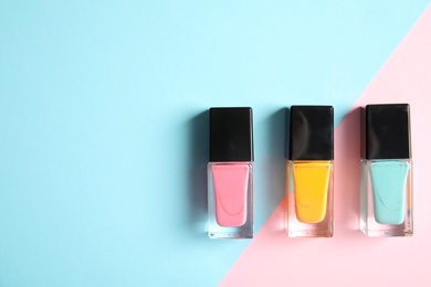 Photo of Bottles of nail polish on color background, top view with space for text