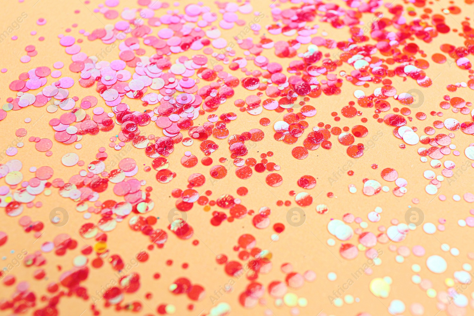 Photo of Shiny bright red glitter on beige background