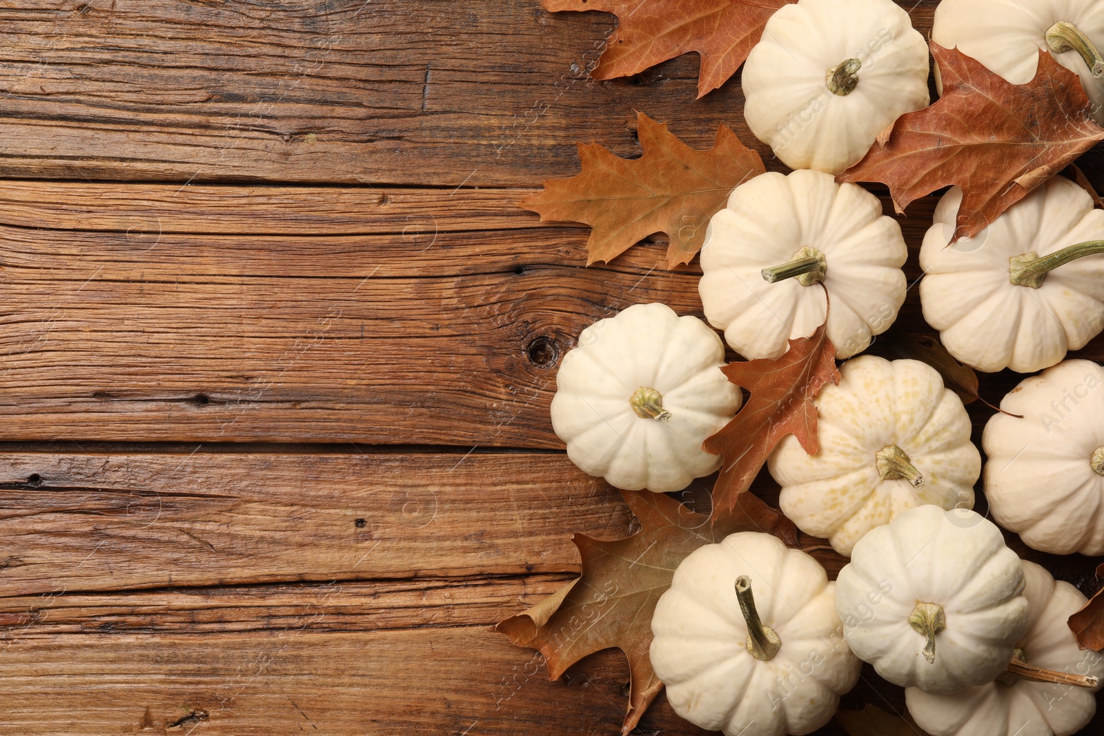 Photo of Fresh ripe pumpkins and dry leaves on wooden table, flat lay. Space for text