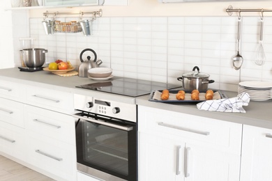 Stylish kitchen interior with modern oven and set of cooking utensils