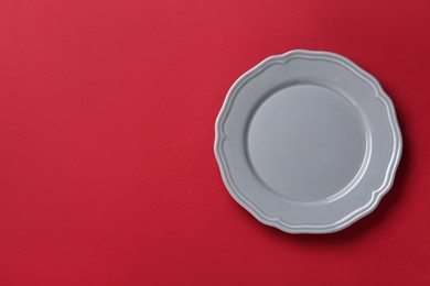 Photo of Clean grey plate on red background, top view. Space for text