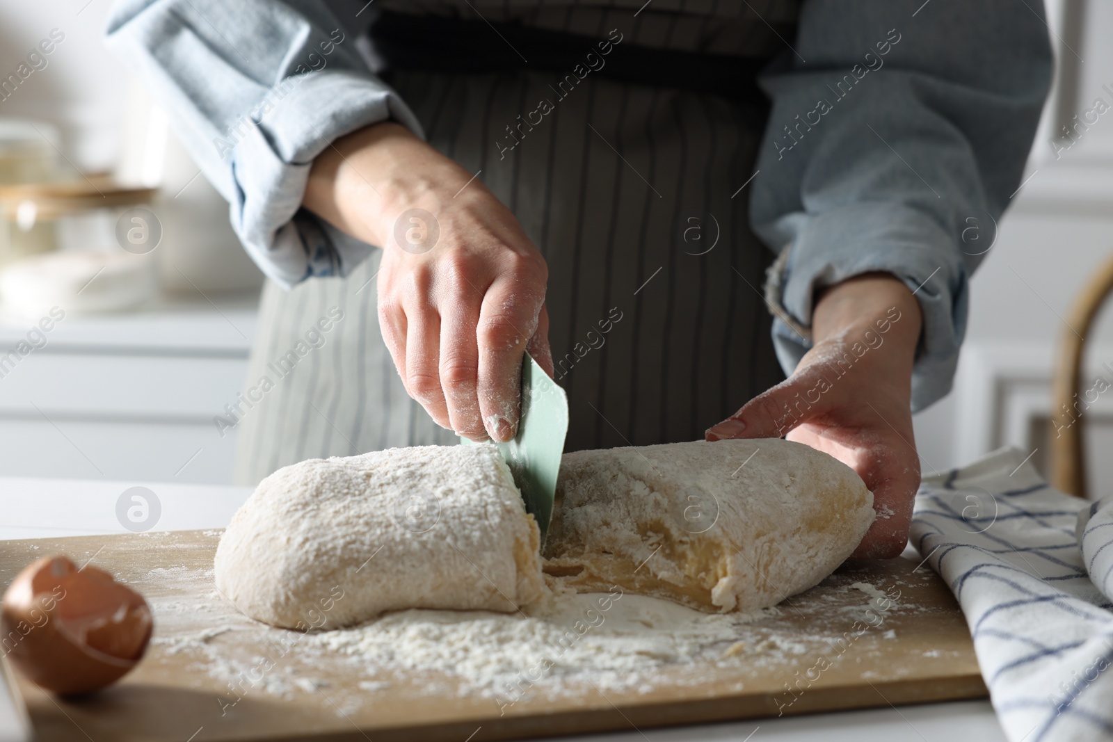 Photo of Woman cutting dough at white wooden table in kitchen, closeup