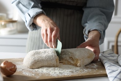 Photo of Woman cutting dough at white wooden table in kitchen, closeup