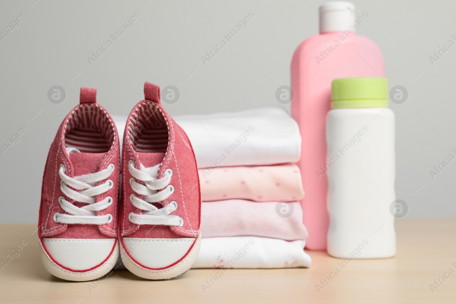 Photo of Baby clothes, booties and accessories on wooden table