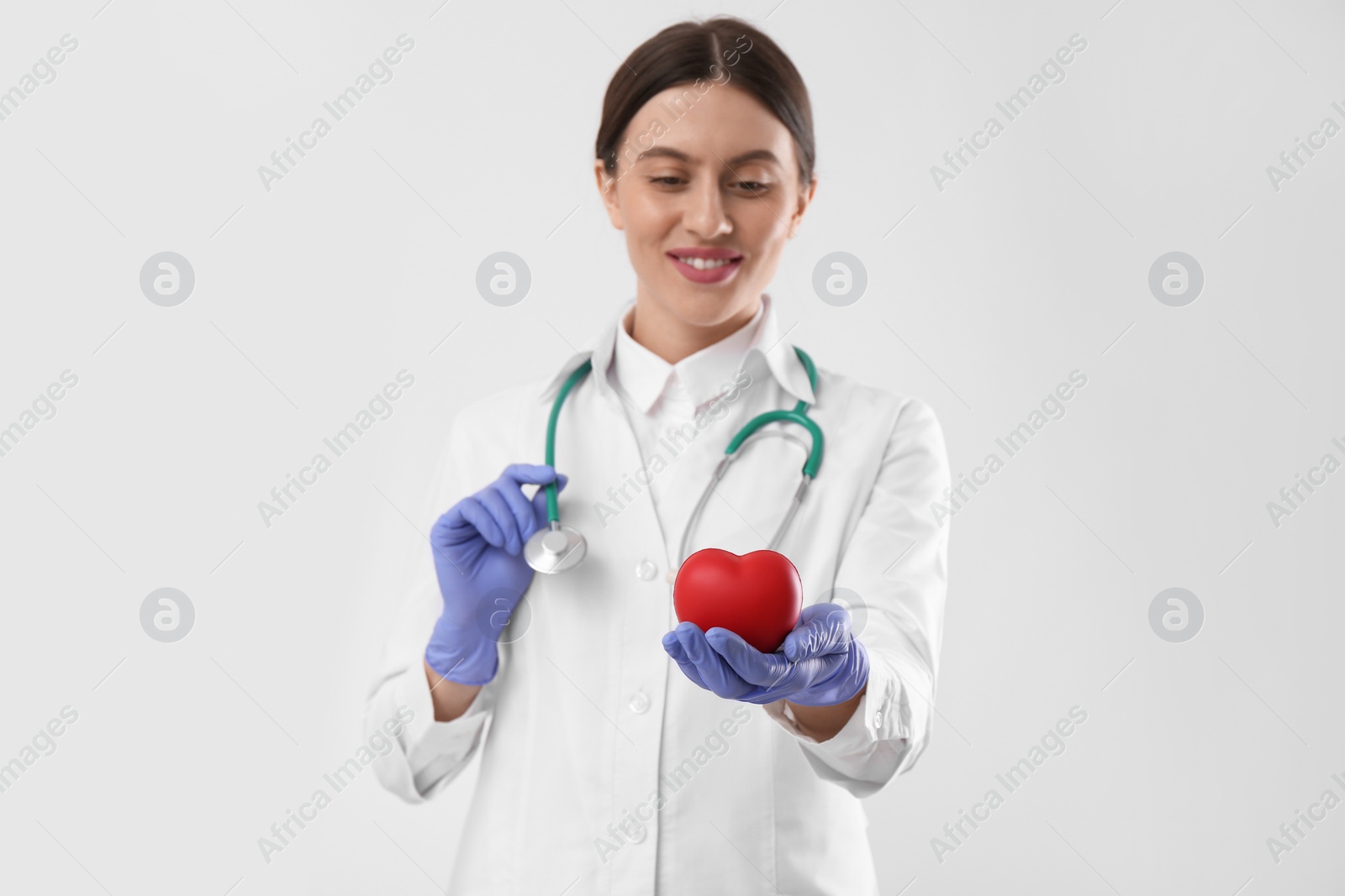 Photo of Doctor with stethoscope and red heart on white background. Cardiology concept