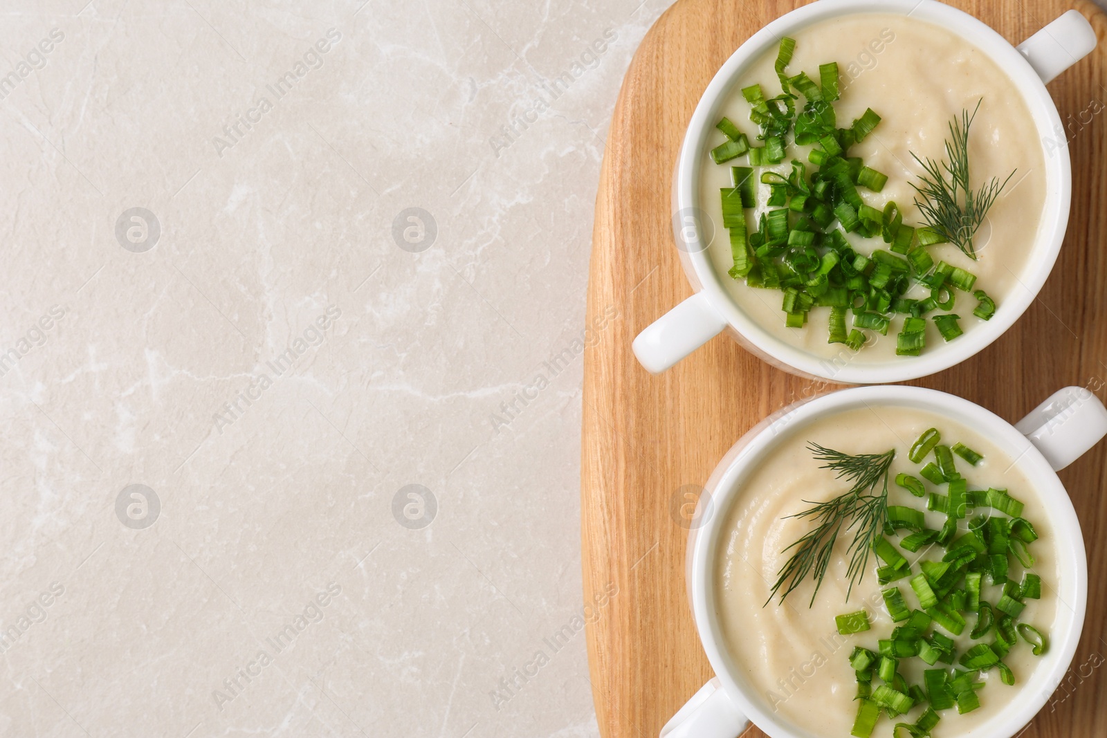 Photo of Bowls with tasty creamy soup of parsnip on light grey background, top view. Space for text