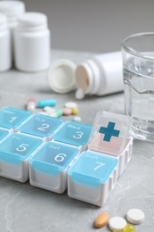 Weekly pill box with medicaments on grey marble table, closeup