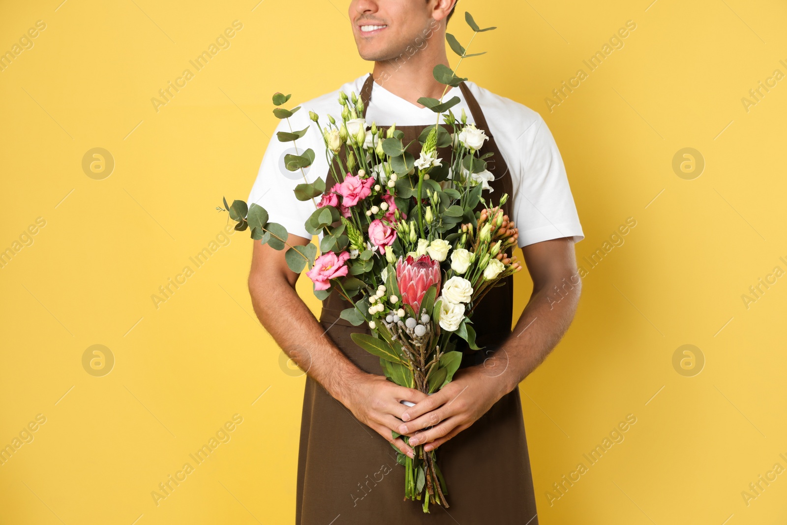 Photo of Florist with beautiful bouquet on yellow background, closeup