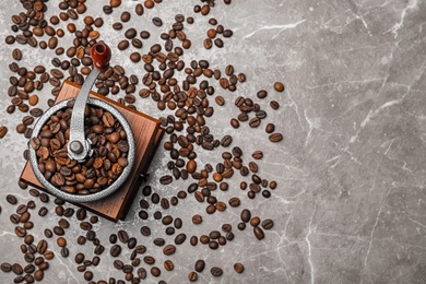 Photo of Coffee grinder with roasted beans on grey background