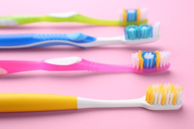 Photo of Many different toothbrushes on pink background, closeup