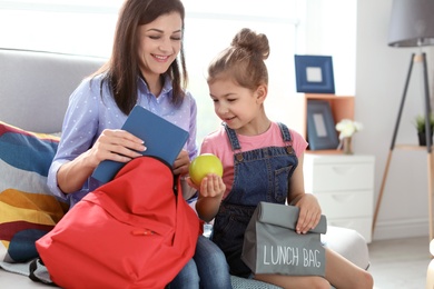 Young woman helping her little child get ready for school at home