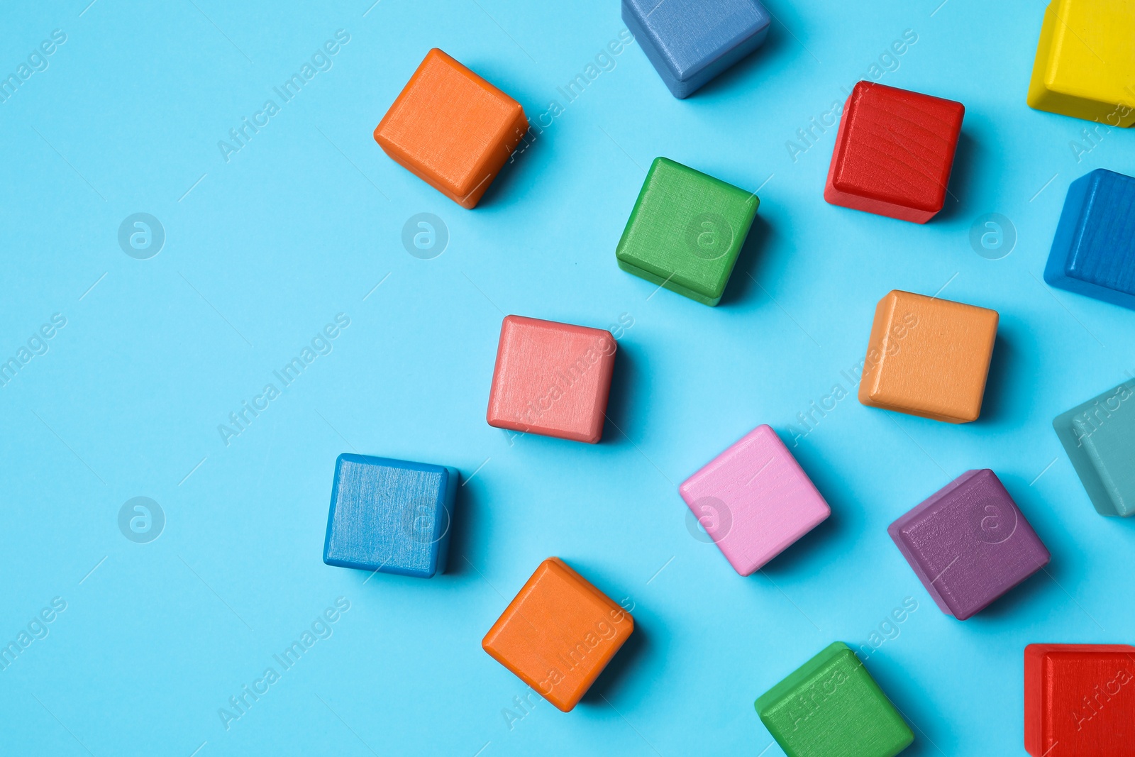 Photo of Blank colorful cubes on light blue background, flat lay. Space for text