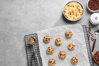 Bowl with dough and uncooked chocolate chip cookies on light grey table, flat lay. Space for text