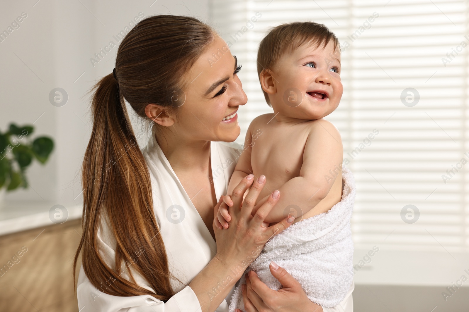 Photo of Happy mother holding her cute baby in towel at home