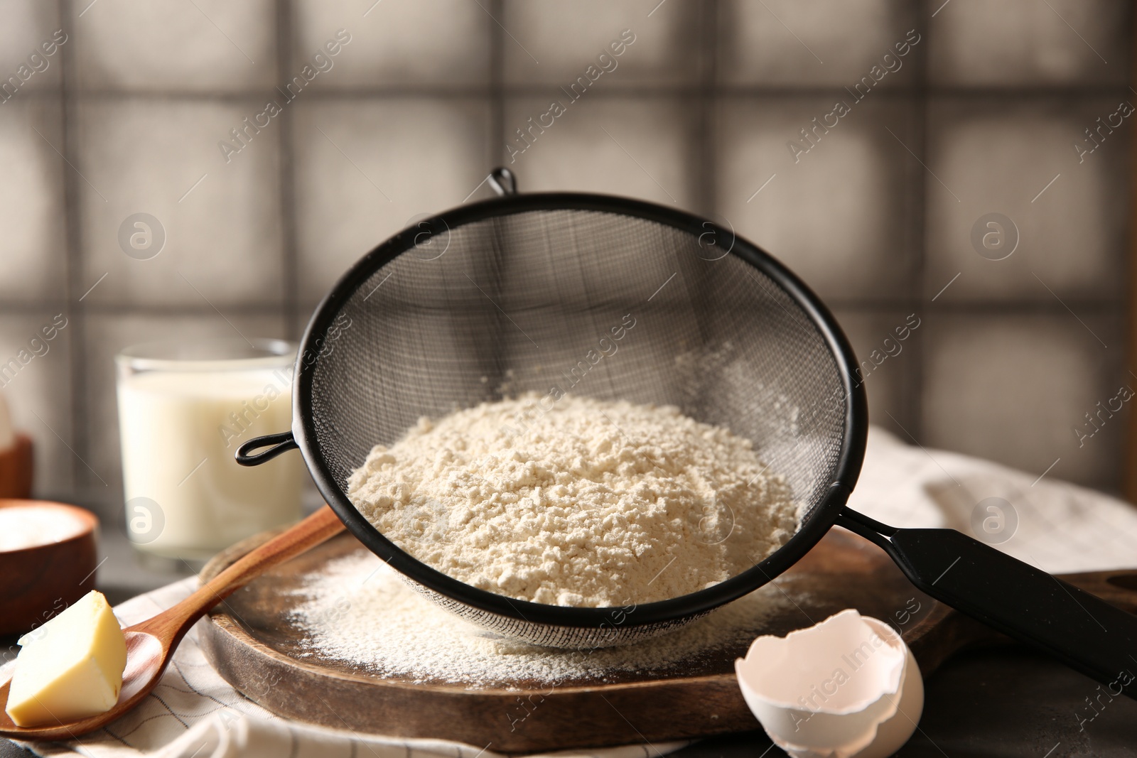 Photo of Making dough. Flour in sieve, spoon and butter on table, closeup