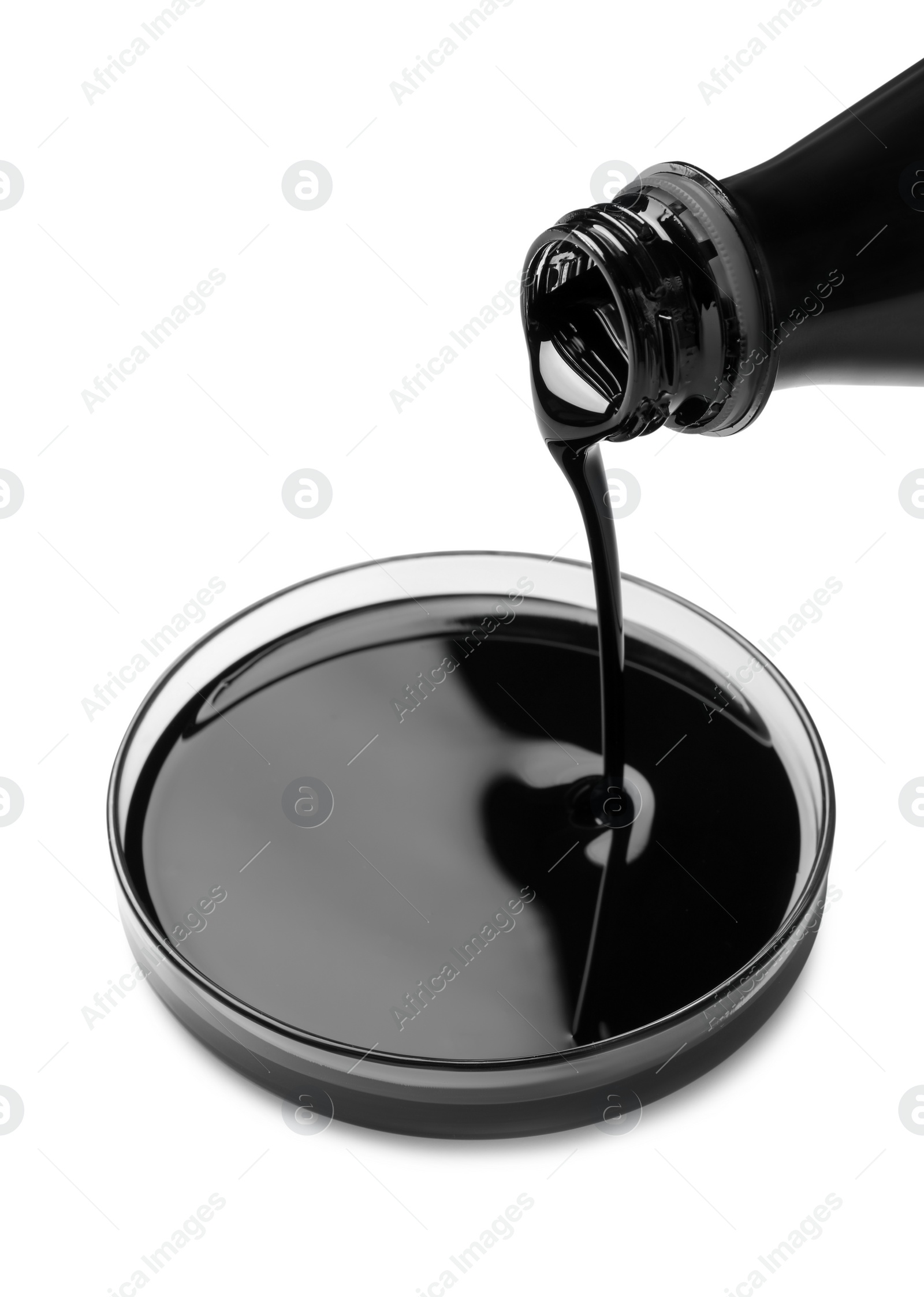 Photo of Pouring black crude oil into Petri dish on white background