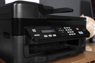Photo of Modern printer on wooden desk at home, closeup