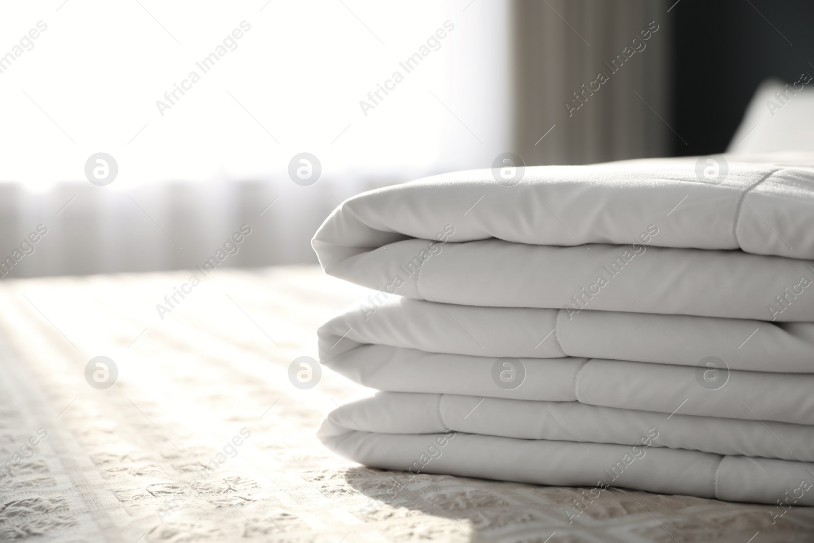 Photo of Folded clean blanket on bed in room, closeup. Space for text