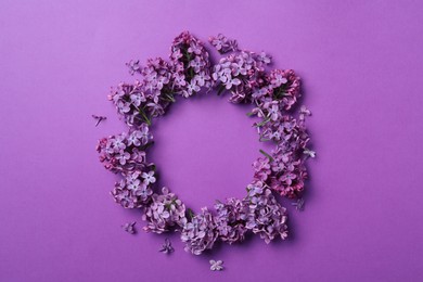 Photo of Frame made with beautiful lilac blossom on purple background, flat lay. Space for text