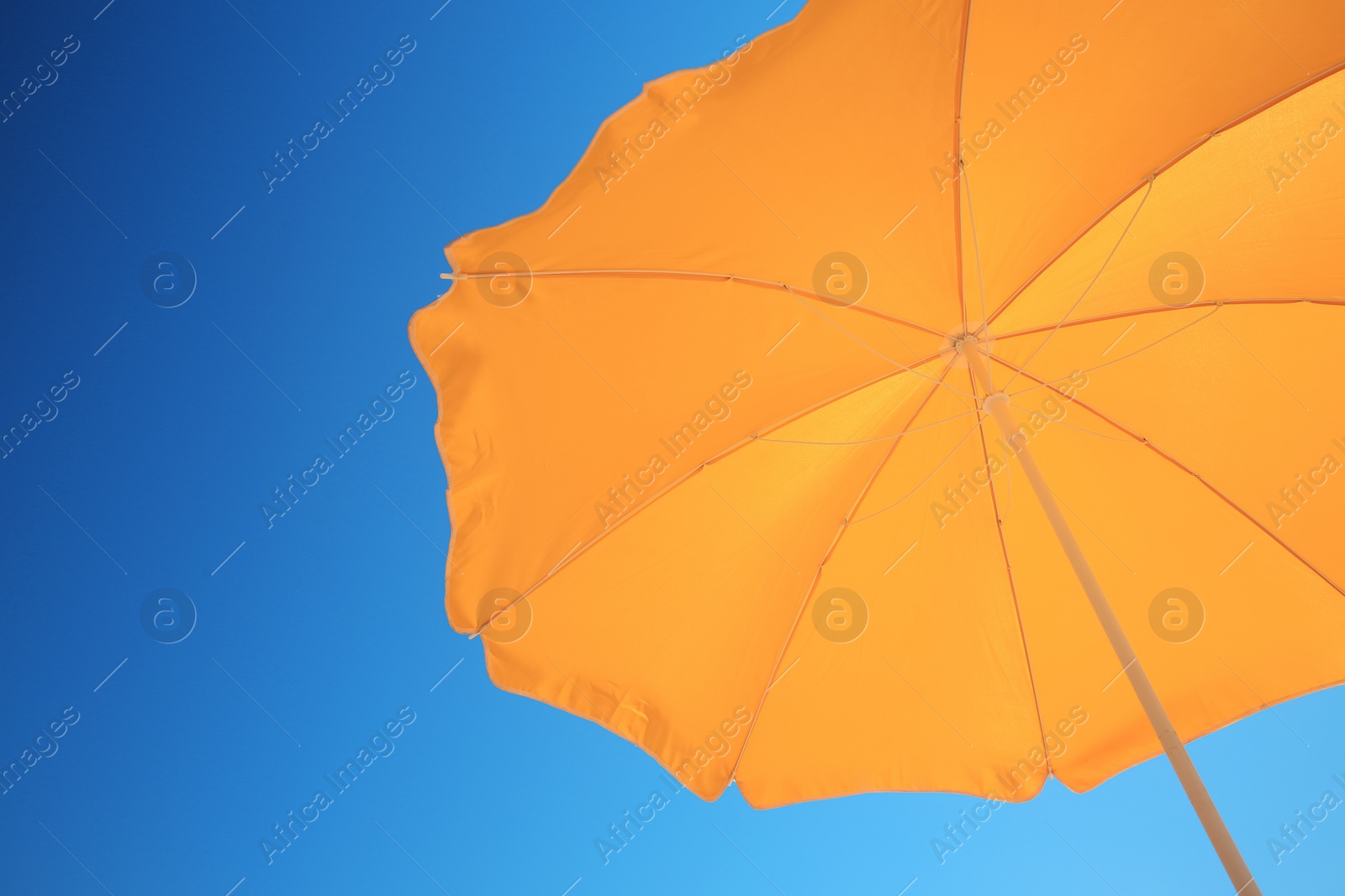 Photo of Orange beach umbrella against blue sky, space for text