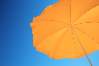 Photo of Orange beach umbrella against blue sky, space for text