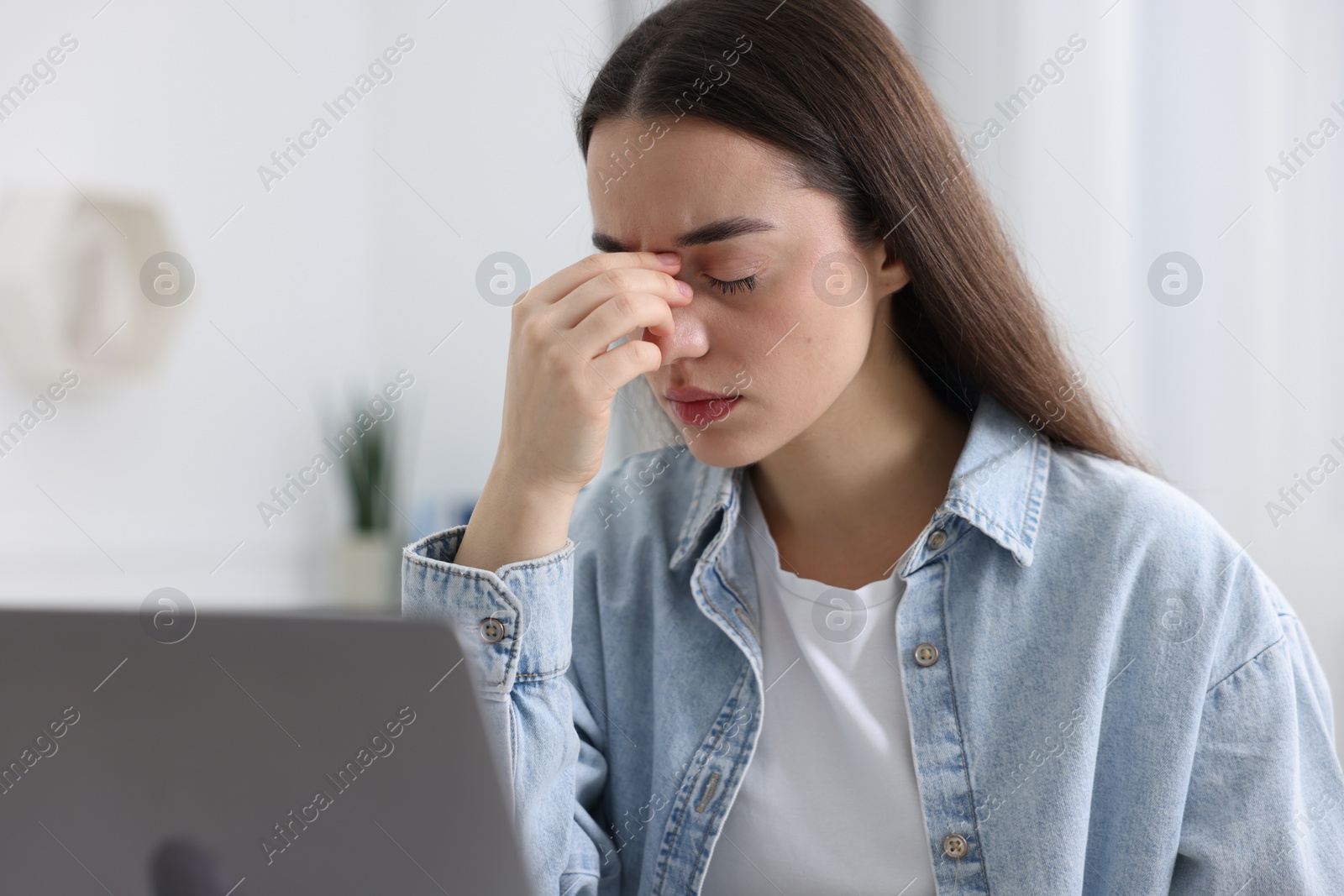 Photo of Woman suffering from headache at workplace in office