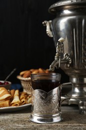 Metal samovar with cup of tea and crepes on wooden table