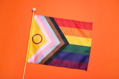 Photo of Bright progress flag on orange background, top view. LGBT pride