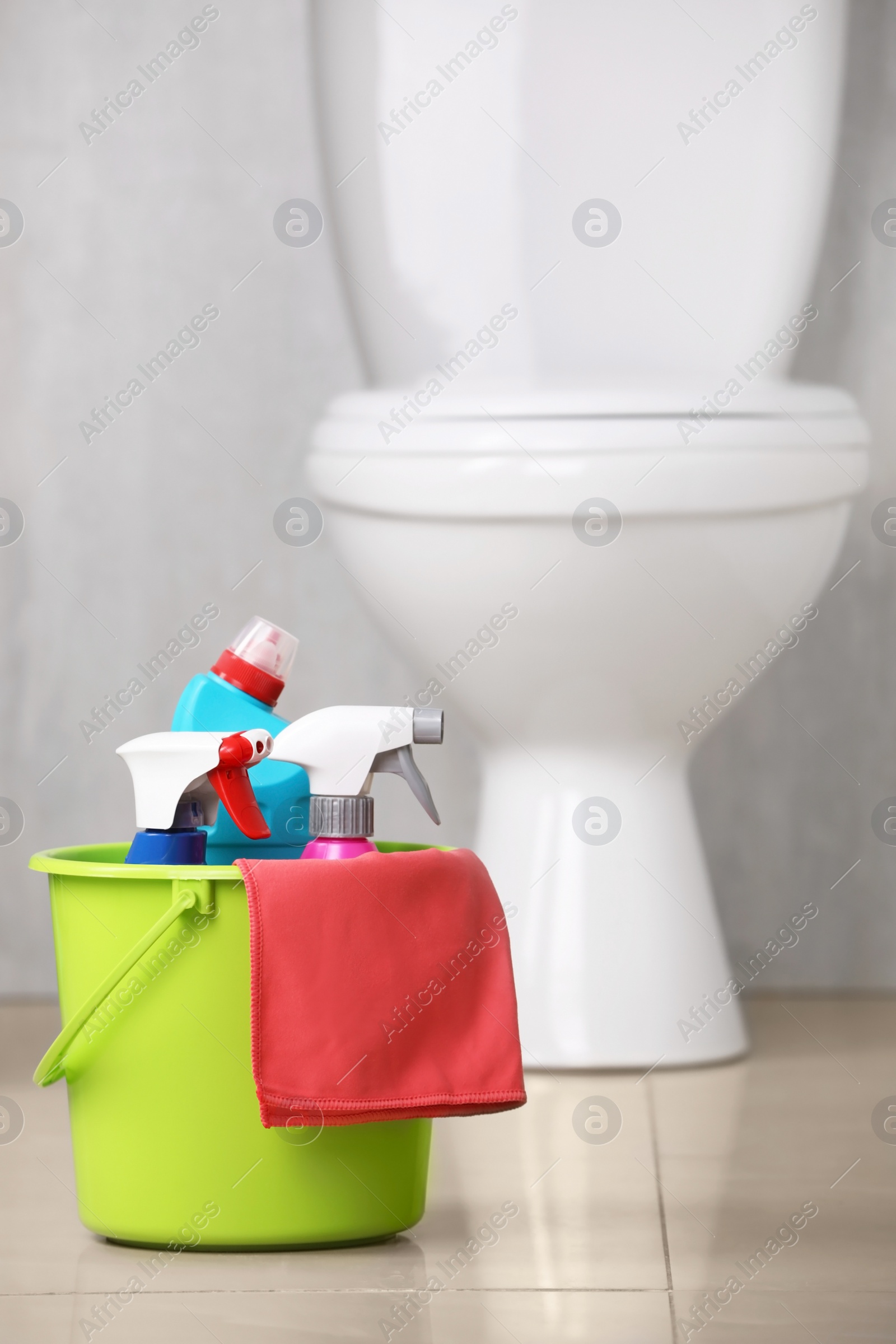 Photo of Bucket with toilet cleaning supplies on floor indoors
