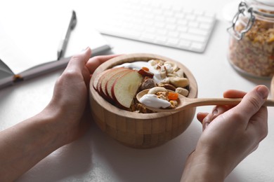 Photo of Woman eating tasty granola at workplace, closeup