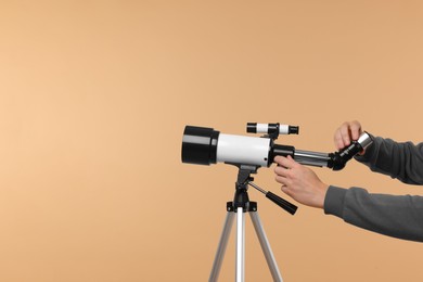 Photo of Astronomer setting up telescope on beige background, closeup. Space for text