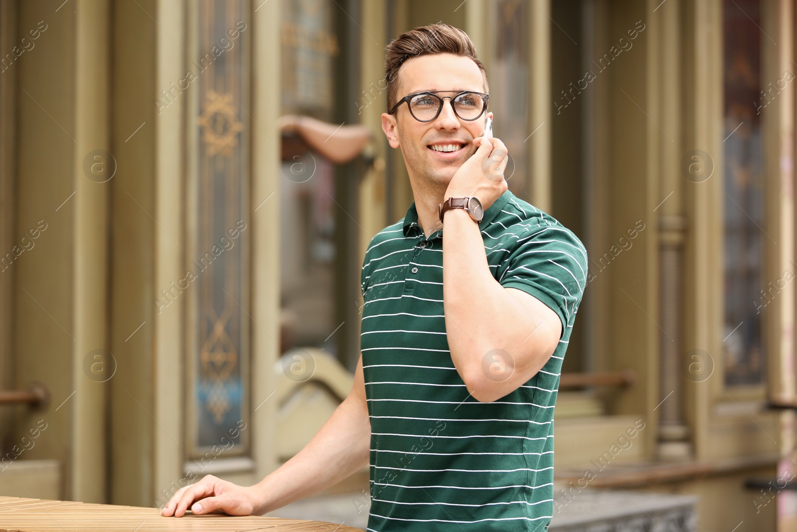 Photo of Attractive young man talking on phone outdoors