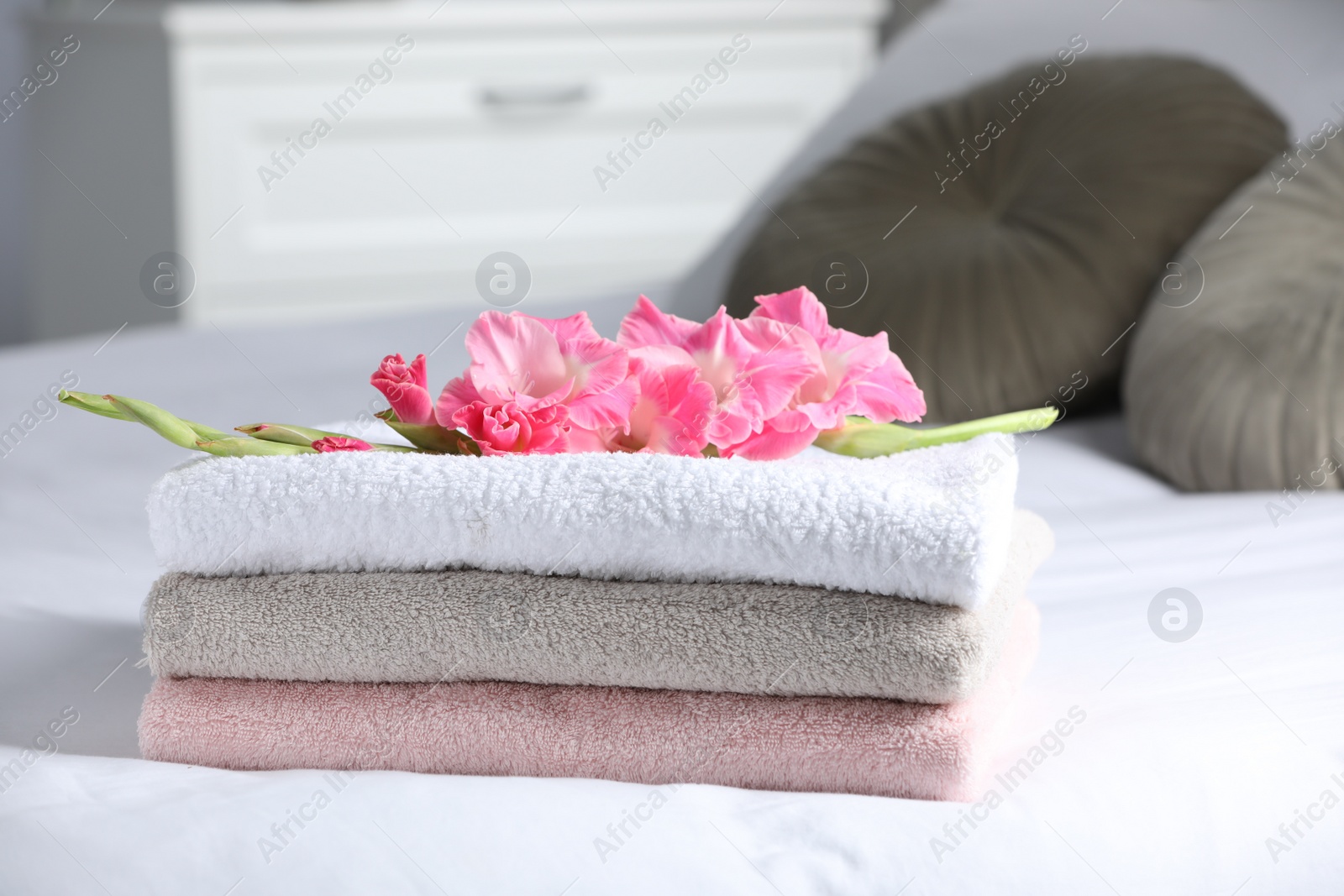 Photo of Terry towels with beautiful flower on bed indoors